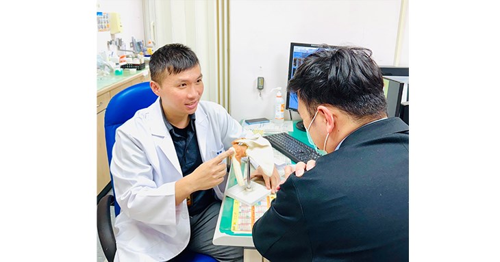 骨科醫師李智堯利用肩關節模型,向患者解說高血糖如何導致關節囊發炎與沾黏。(圖片提供/臺北市立聯合醫院)